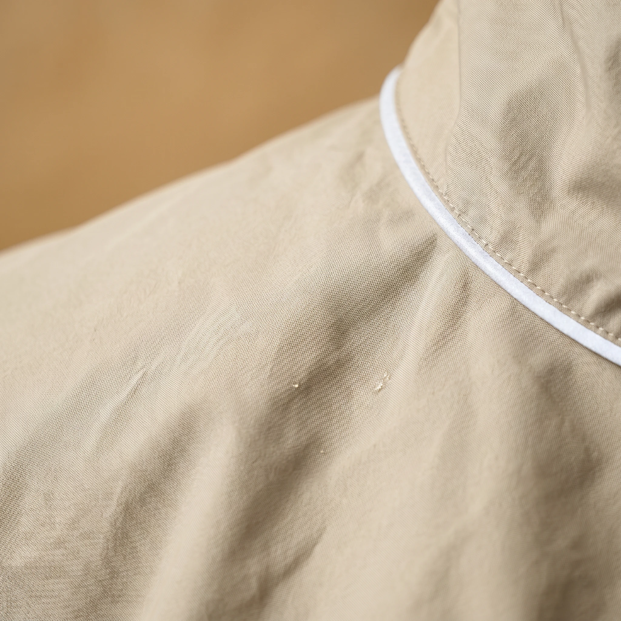Beige waterproof dog coat for Dobermans, featuring clean stitching and a minimalist hood design with white trim, crafted for deep-chested breeds in soft, natural lighting.