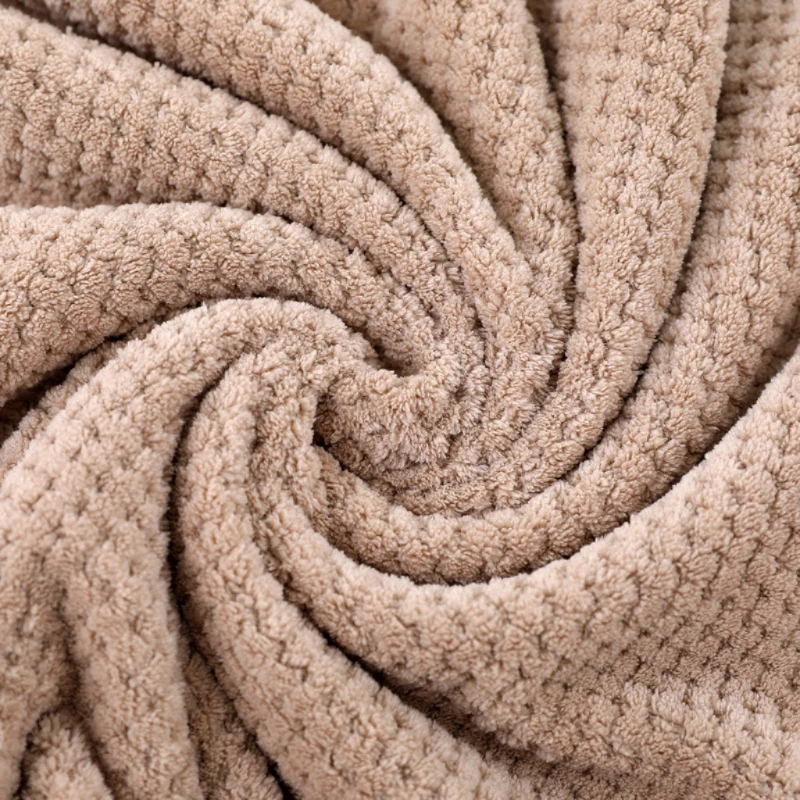 Soft beige waffle-weave coral fleece towel swirled in gentle folds, showcasing its plush texture and calm, tactile warmth in a minimalist, wabi-sabi aesthetic.